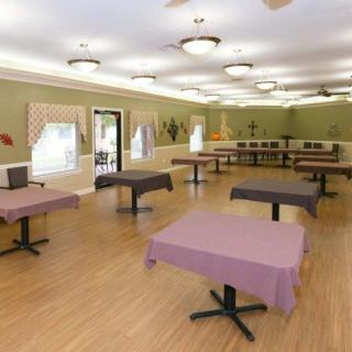 An empty dining area with tables covered in purple tablecloths and a wooden floor.