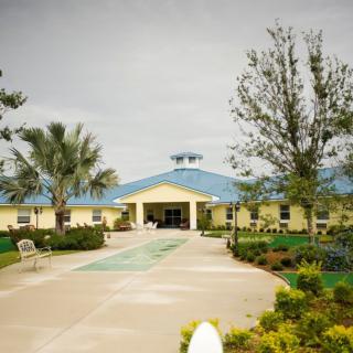 A well-maintained building with a blue roof surrounded by trees and landscaped pathways.