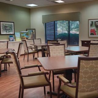 A well-lit dining or meeting room with multiple tables and chairs, adorned with artwork on the walls.