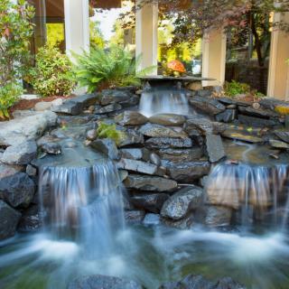 A serene outdoor waterfall cascading over rocks in a garden setting.