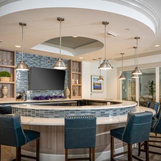 A modern bar area with blue seating, pendant lights, and a television.