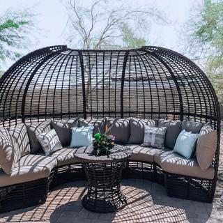 Cozy outdoor wicker seating area with cushions under a dome-shaped structure.