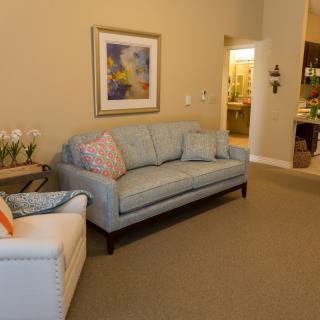 A cozy living room with a sofa, armchair, and decorative elements like artwork and flower vases.