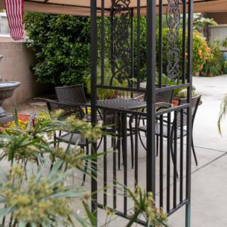 A cozy patio setup featuring a table and chairs under an umbrella, surrounded by plants.
