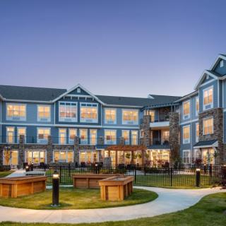 A large residential building with landscaped gardens at twilight.