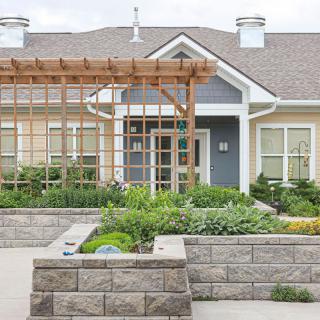 A modern residential house with a landscaped garden and pergola at the entrance.