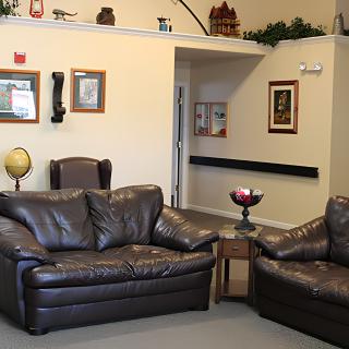 A cozy living room with leather couches, an armchair, and various wall decorations.