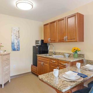 A cozy kitchenette with wooden cabinets, a dining area, and modern appliances.
