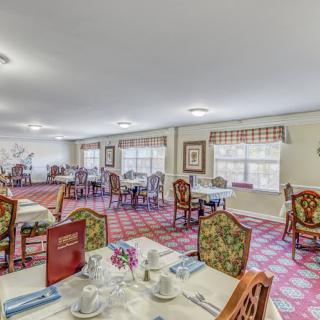 A spacious dining room with elegantly set tables and floral-patterned chairs.