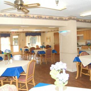 A cozy dining area with neatly arranged tables and chairs, featuring blue tablecloths and floral decorations.