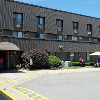 A hotel building with a parking lot in front, captured on a sunny day.
