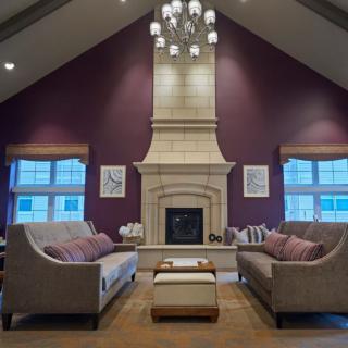 A modern living room with a central fireplace, elegant sofas, and a stylish chandelier.
