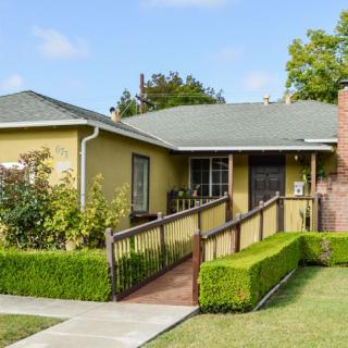 A single-story house with a wheelchair ramp and well-manicured front yard.