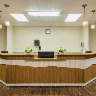 A reception desk in a well-lit office space with decorative flowers.