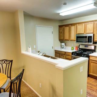 A modern kitchen with an open layout featuring wooden cabinets, stainless steel appliances, and an adjacent dining area.
