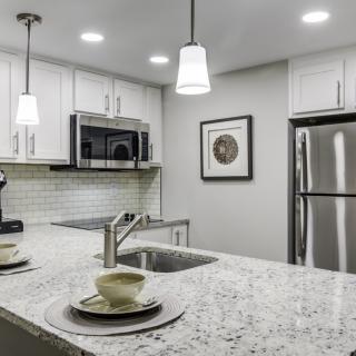 A modern kitchen with stainless steel appliances and pendant lighting.