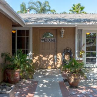 A welcoming house entrance with potted plants and a decorative wooden door.