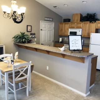 A cozy kitchen and dining area with a small table, chairs, wood cabinets, and a chandelier.