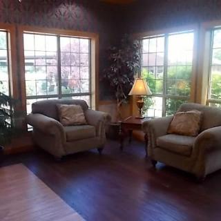 A cozy living room area with two armchairs, a small table, and large windows letting in natural light.