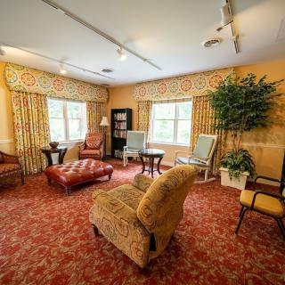 A cozy living room with an elegant interior design featuring comfortable chairs, a sofa, and warm lighting.