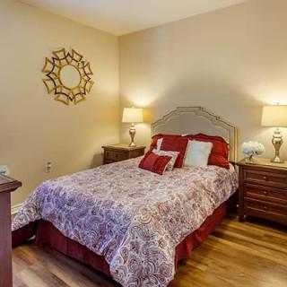 A cozy bedroom with a neatly made bed, decorative pillows, and two bedside tables with lamps.