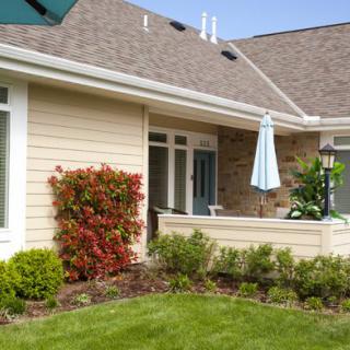 A charming house with a well-maintained garden and a cozy patio area featuring an umbrella.