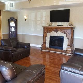 A cozy living room featuring a fireplace with an ornate mantelpiece, leather sofas, and a television mounted above the hearth.
