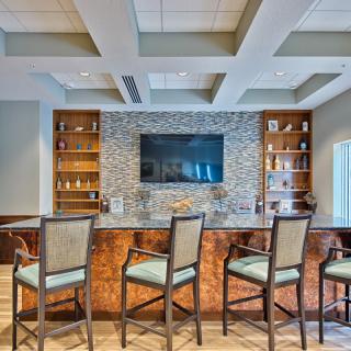 Modern bar area with stylish seating and a large television.