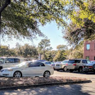 A busy parking lot filled with various cars under a clear blue sky.