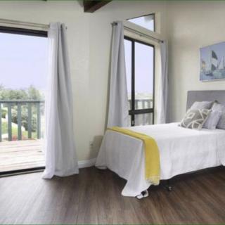A cozy bedroom with large windows and modern decor.