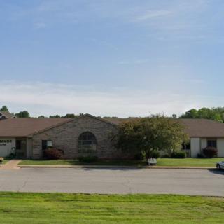 A suburban residential building with a driveway and a well-maintained lawn.
