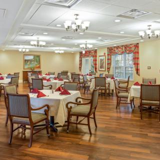 An elegant dining room interior with neatly arranged tables and chairs on a wooden floor.