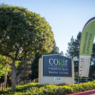 Entrance sign for COGIR of North Bay Senior Living surrounded by greenery.