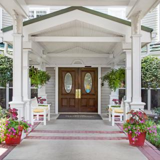 A charming porch entrance with potted plants and wooden doors.