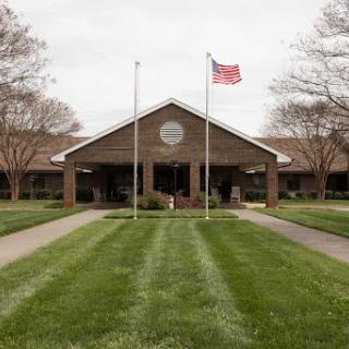 A well-maintained building with an American flag in front, set against a backdrop of green grass.
