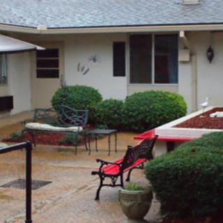 A cozy courtyard with benches, a table, and surrounding greenery.