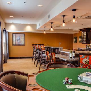 A cozy room featuring a poker table and a bar area with ample seating.