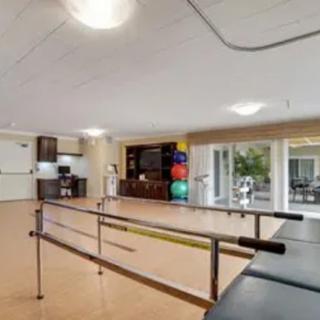 A spacious physical therapy room equipped with parallel bars and exercise balls.
