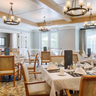 An elegant restaurant dining room with neatly arranged tables and classic chandeliers.