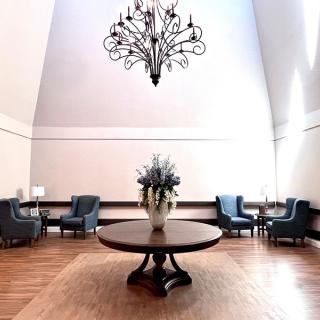 A spacious lobby with a central round table, elegant chandelier, and comfortable seating.