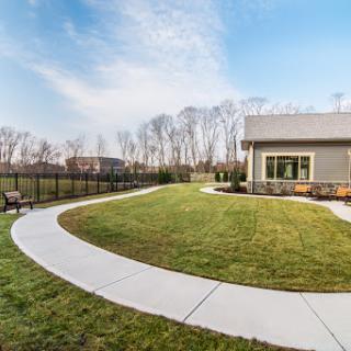 A serene outdoor space featuring a curved pathway, well-maintained lawn, and modern building under a clear sky.