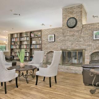 A cozy modern living room featuring a brick fireplace, stylish armchairs, and a well-stocked bookshelf.