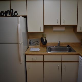 A cozy kitchen with cream cabinets and a refrigerator next to a sink.