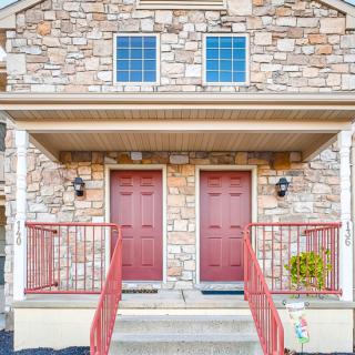 A symmetrical stone facade house with two red front doors.