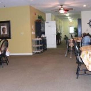 A spacious dining area with tables and chairs arranged neatly, featuring a ceiling fan and warm lighting.