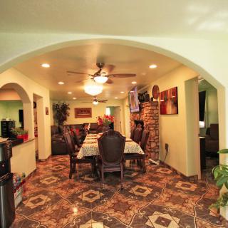 A cozy dining room with a large table set under an archway, featuring a ceiling fan, brick accents, and striking tile flooring.