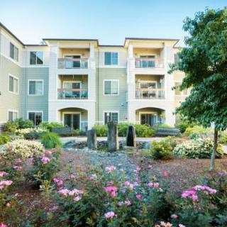 A residential apartment building with beautifully landscaped gardens and vibrant flowers.