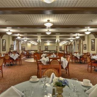 An elegant and spacious restaurant dining area with neatly arranged tables and chairs, illuminated by soft ceiling lights.