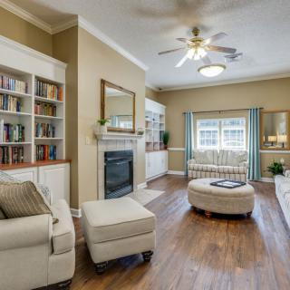 A cozy living room featuring a comfortable sofa, wooden floors, bookshelves, and a fireplace.