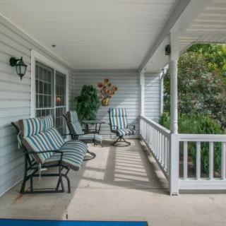 A cozy covered porch with cushioned chairs and a small table, perfect for relaxation.